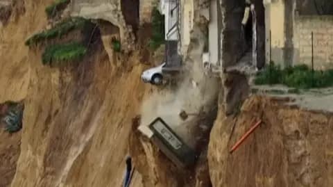 A car teetering on the edge of a drop after a landslide