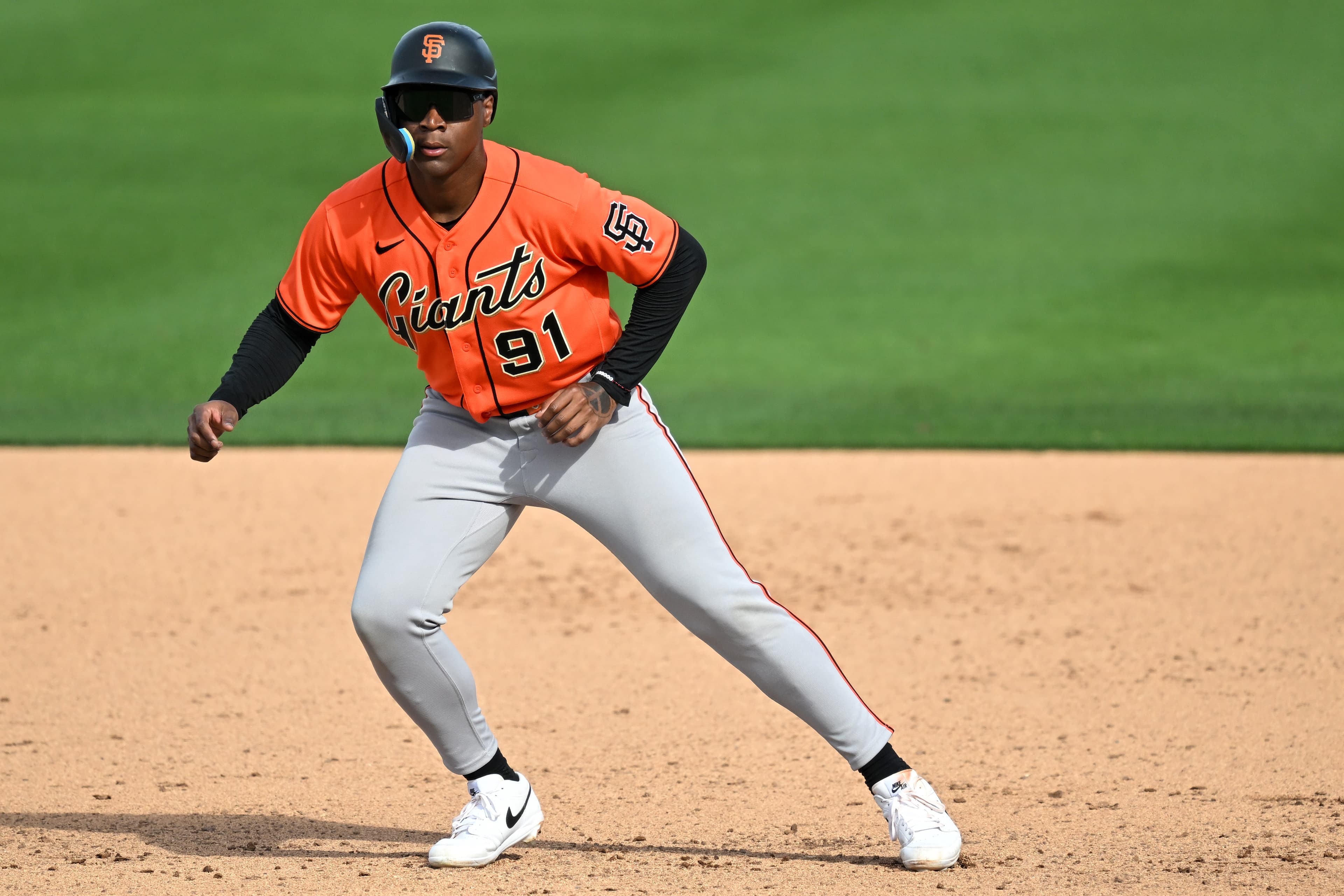 Bo Davidson taking a lead off a base in an orange Giants jersey. 