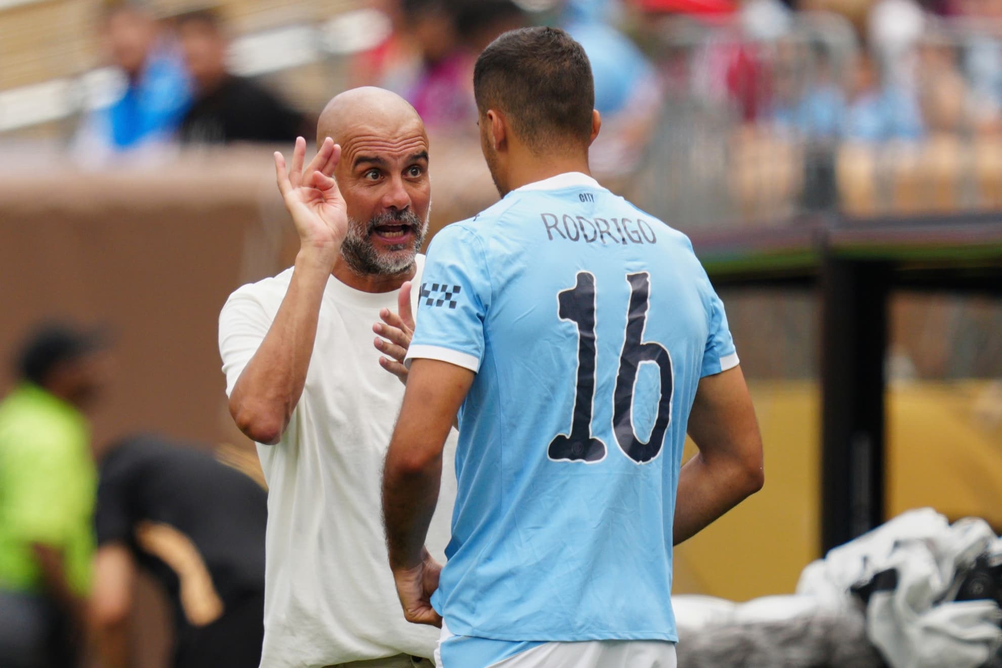 Rodri y Guardiola charlan durante un partido.