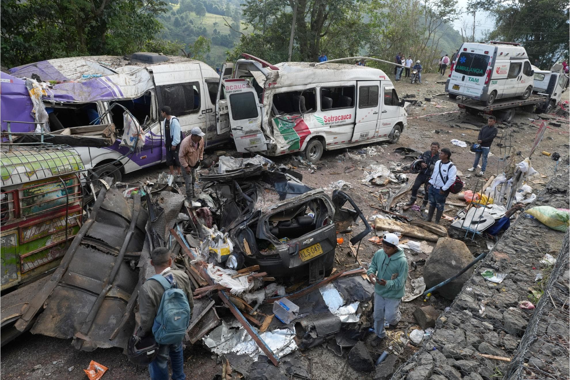 Personas observan este domingo vehículos destruidos por un atentado ocurrido en la Vía Panamericana en Cajibío (Colombia).