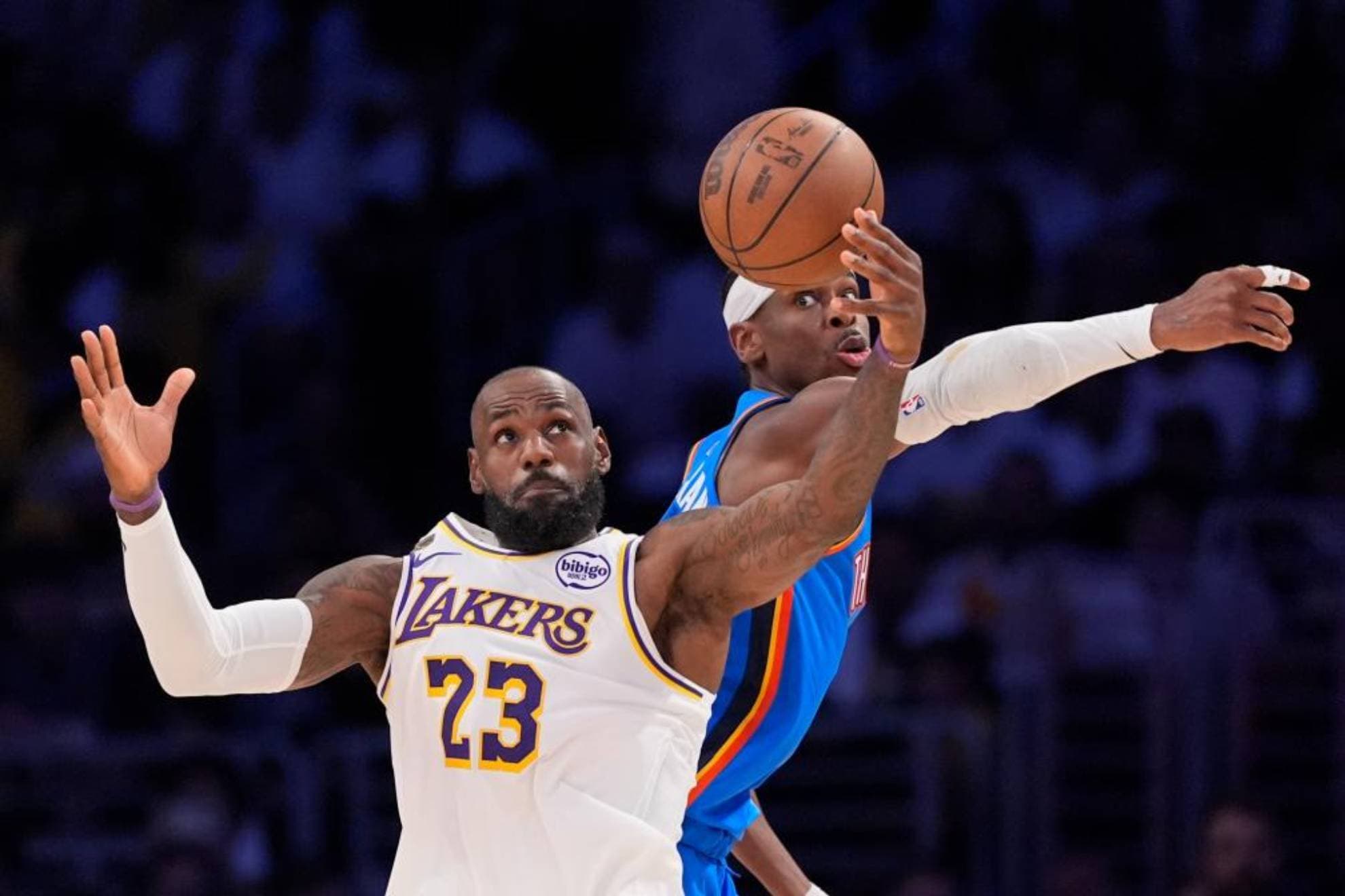 LeBron James y Shai Gilgeous-Alexander luchan por atrapar un rebote.