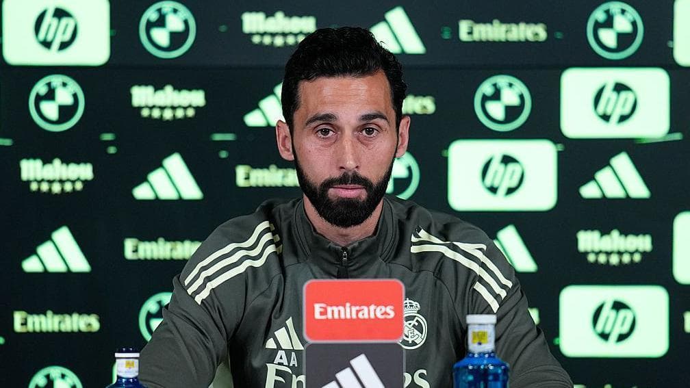 Alvaro Arbeloa speaks at a Real Madrid news conference, in dark green training outfit with light green trim, in front of an advertising board in same colours
