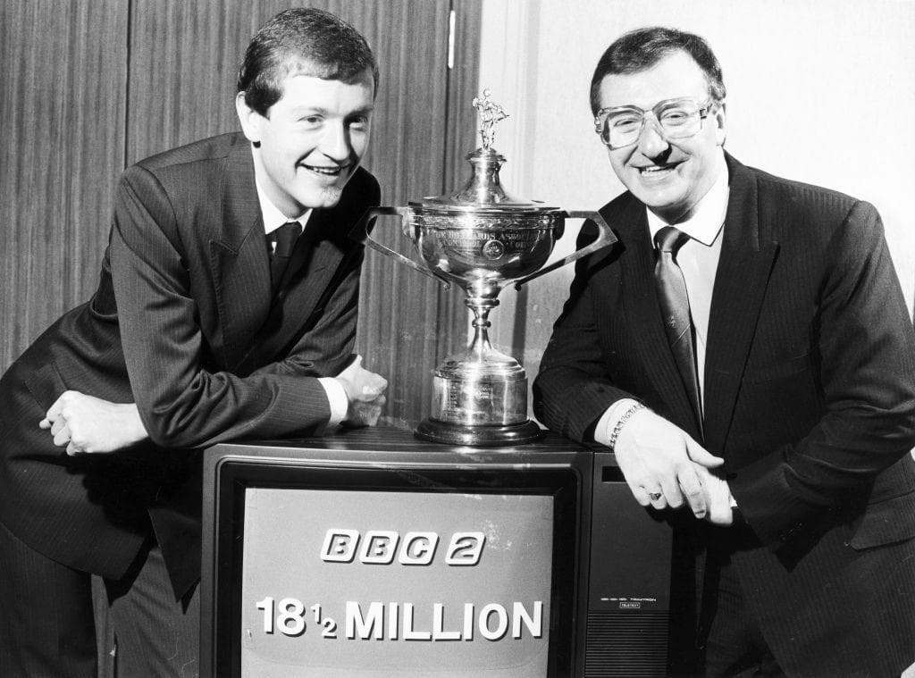 Steve Davis and Dennis Taylor pose with the World Championship trophy and a television on which the screen says 'BBC 2 18 ½ million"