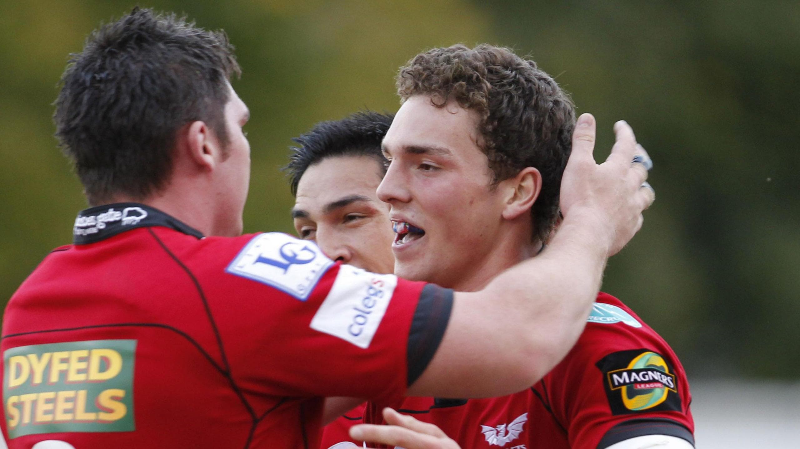 George North (R) celebrates with Rob McCusker (L) and Regan King (obscured) after scoring a try for Scarlets