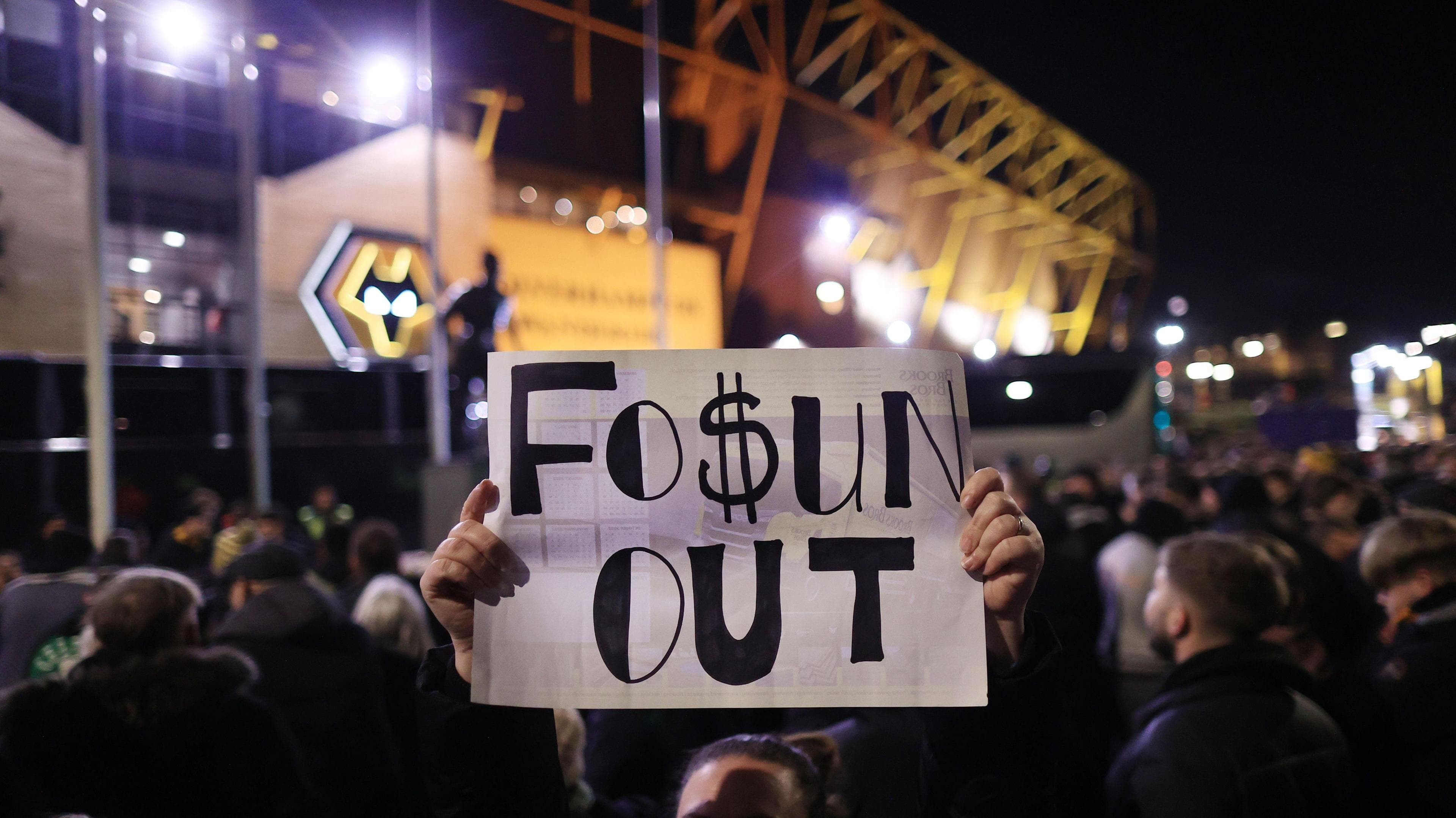 A Wolves fan protests with a sign that reads 'Fo$un out'