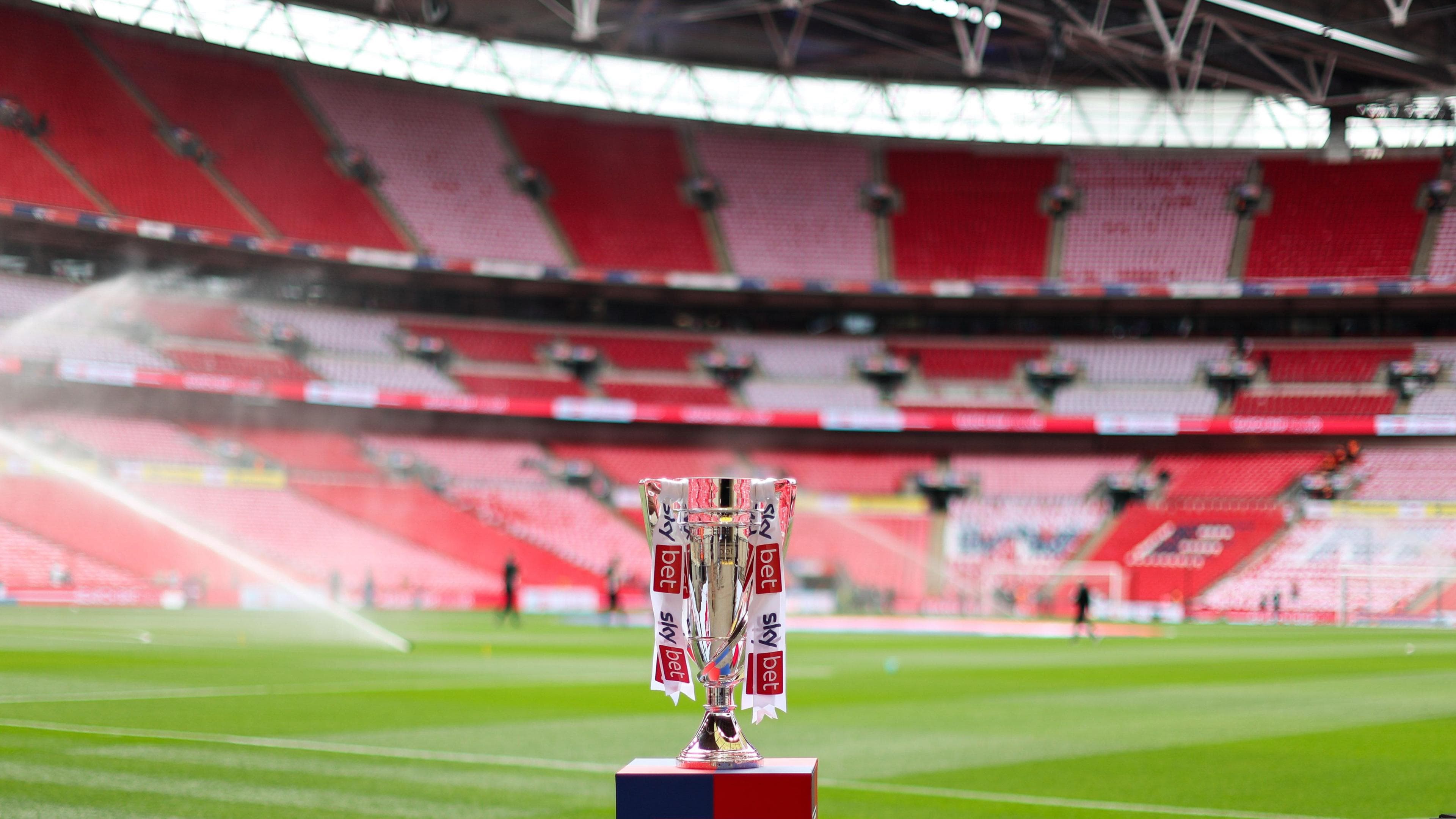 The Championship play-off final trophy on a stand at Wembley Stadium with the pitch and red seats visible behind