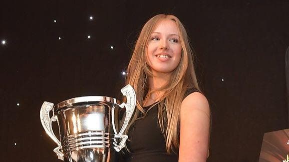 Maisy Creed smiles while holding a trophy