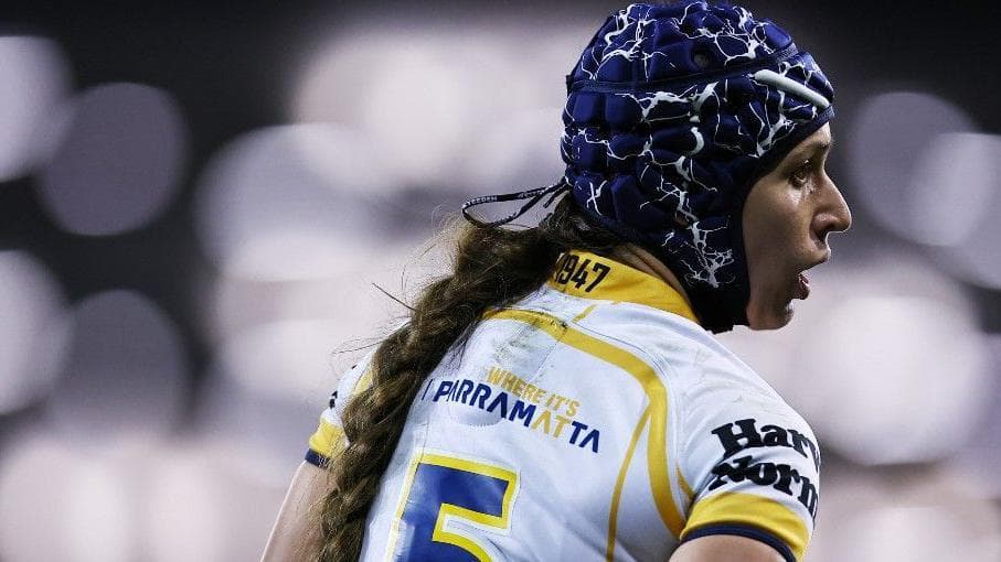 Monique Donovan pictured mid-game wearing a scrum-cap and long pony-tail, in a match-fit Parramatta Eels player jersey.