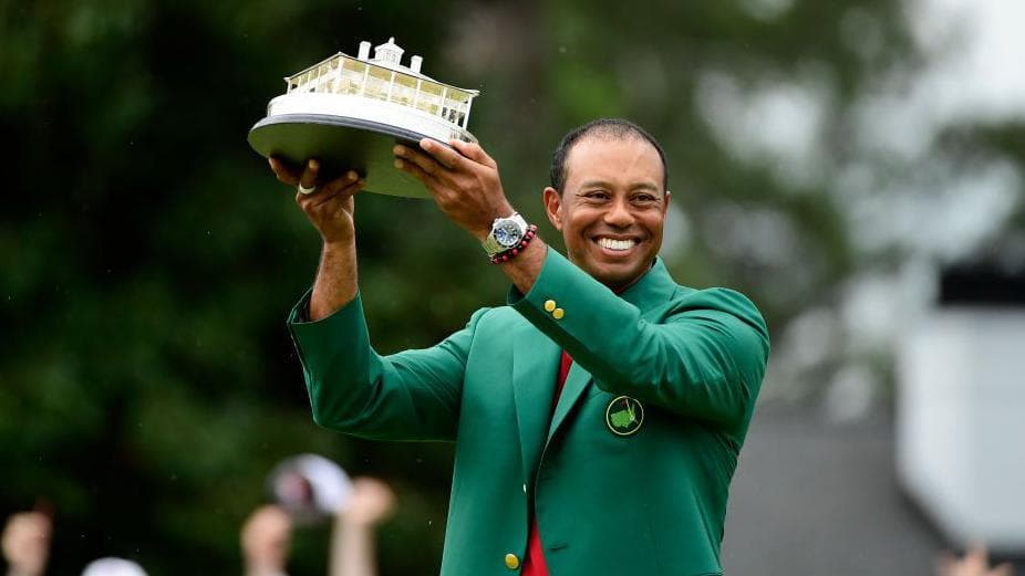 Tiger Woods lifts the Masters trophy while wearing the green jacket at Augusta
