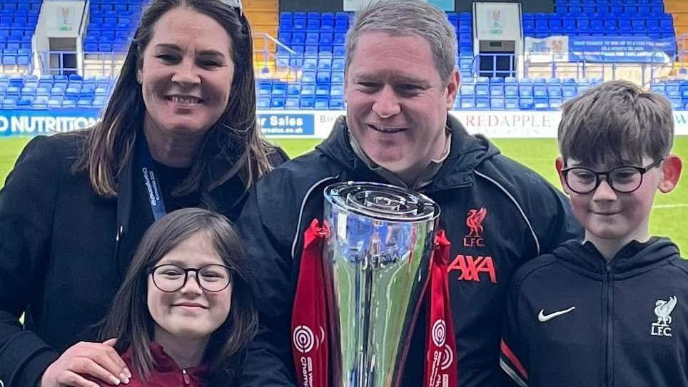 A photograph of Liverpool Women manager Matt Beard celebrating the Championship trophy win with his family