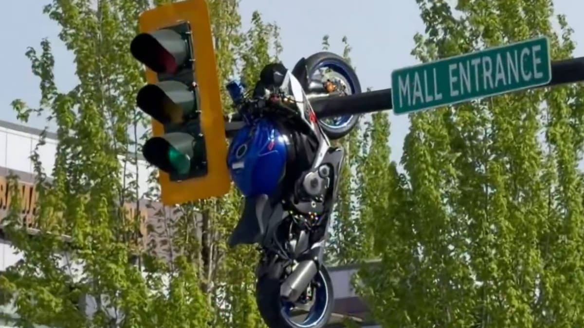 Un motorista choca en un cruce y su moto acaba colgada de un semáforo