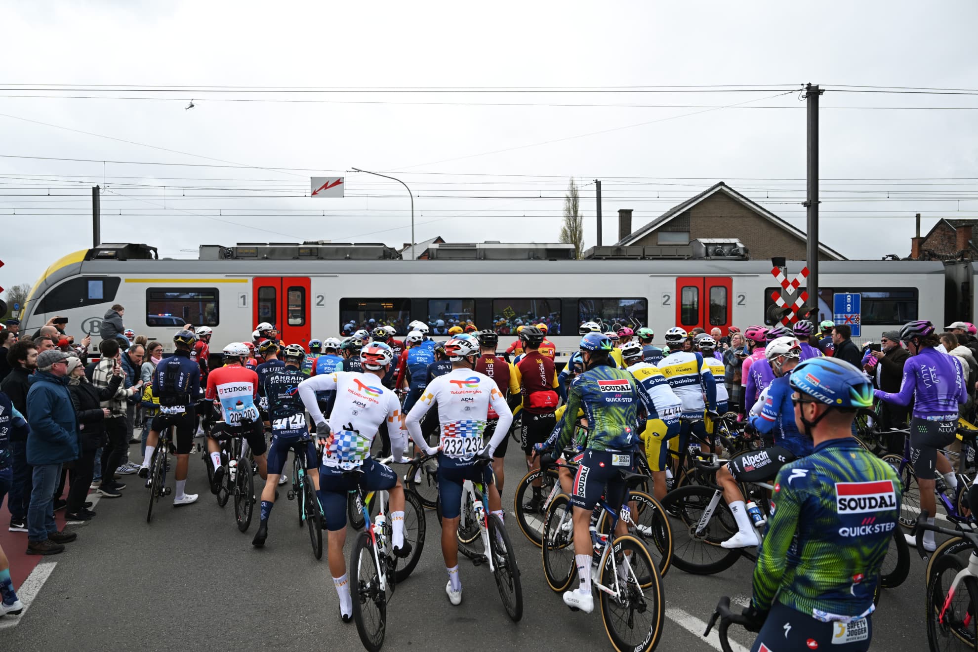 Los ciclistas, detenidos por el paso del tren durante el Tour de Flandes.