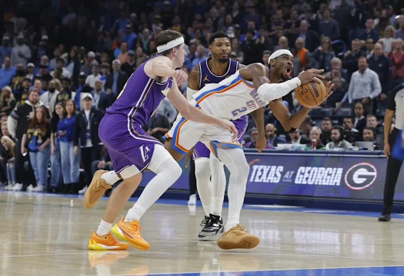 Oklahoma City Thunder guard Shai Gilgeous-Alexander (2) drives between Los Angeles Lakers guard Austin Reaves (15)